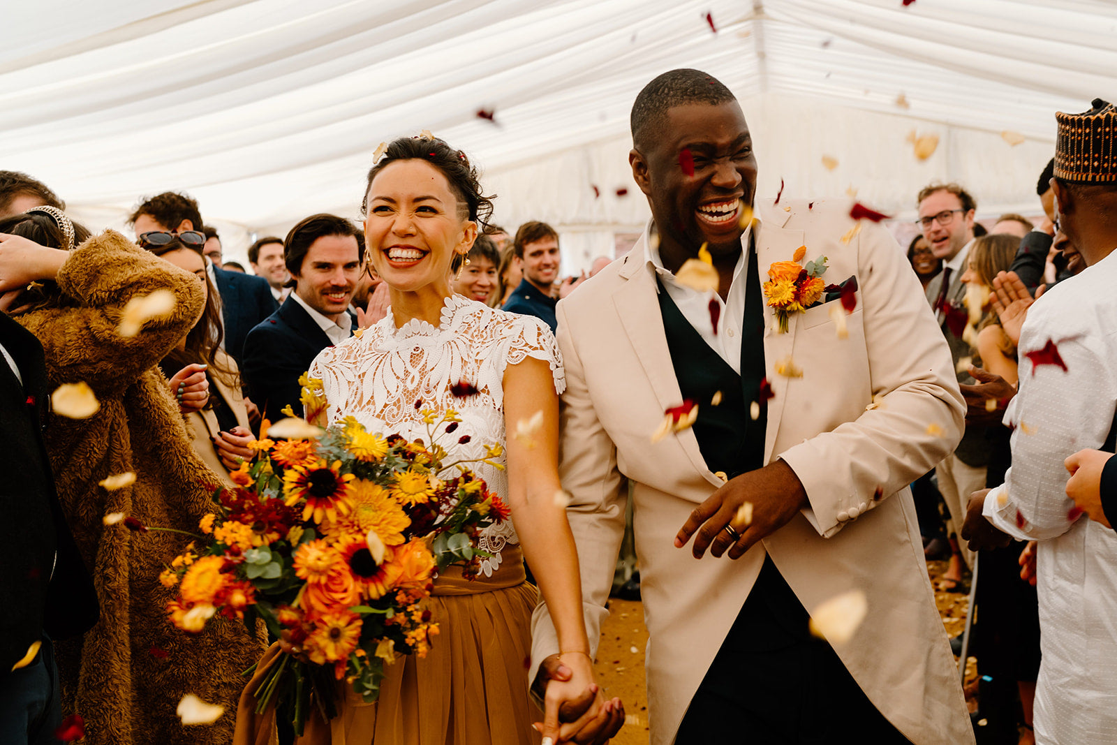Wedding in the Midlands, Derbyshire. Couple walking down the aisle with autumnal coloured flowers. Orange dahlias, kangaroo paw, rudbekia, helecrysium and straw flowers.