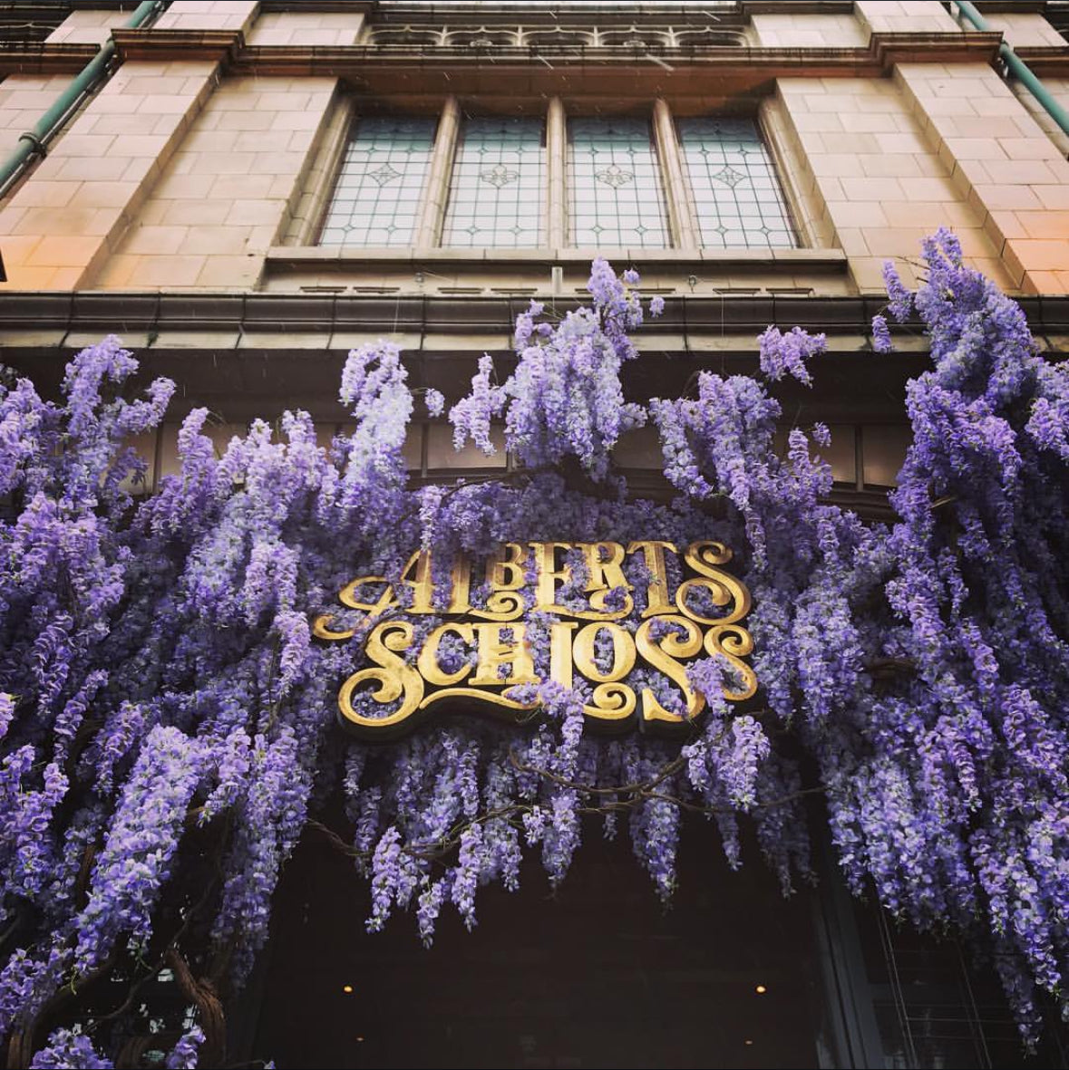 Hanging wisteria floral installation outside Alberts Schloss restaurant in Manchester. Large outdoor flower installation.