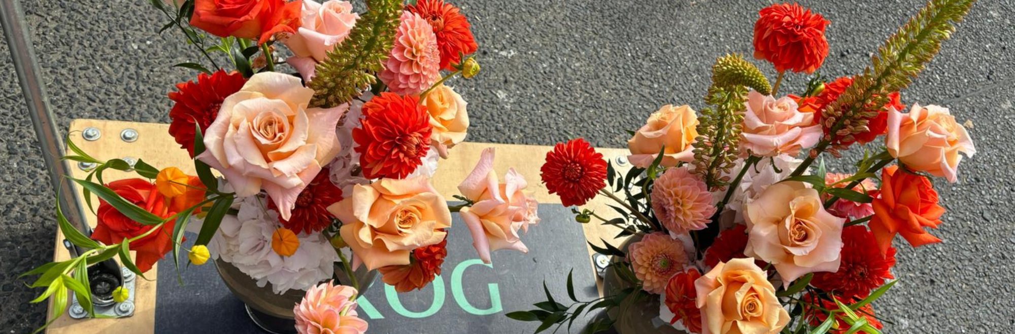 Image of flowers in Manchester on a trolley with orange dahlias, peach roses, eremurus, and peach  dahlias. Modern and alternative for a wedding.