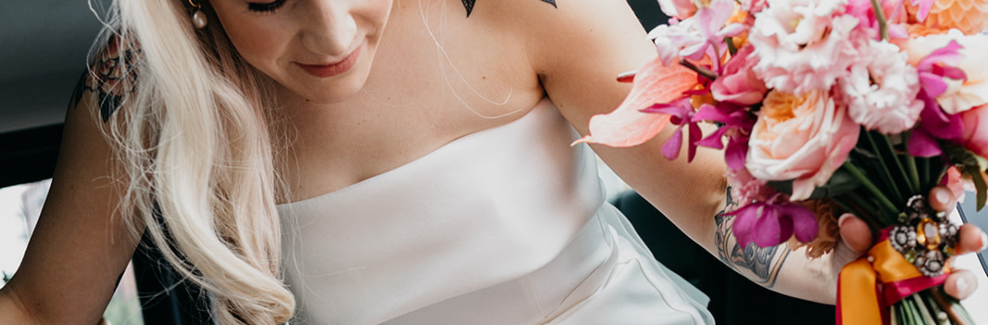 Woman leaving car with colourful modern bridal bouquet in Manchester. Peach roses, anthurium, pink lisianthus, pink orchids. alternative wedding.
