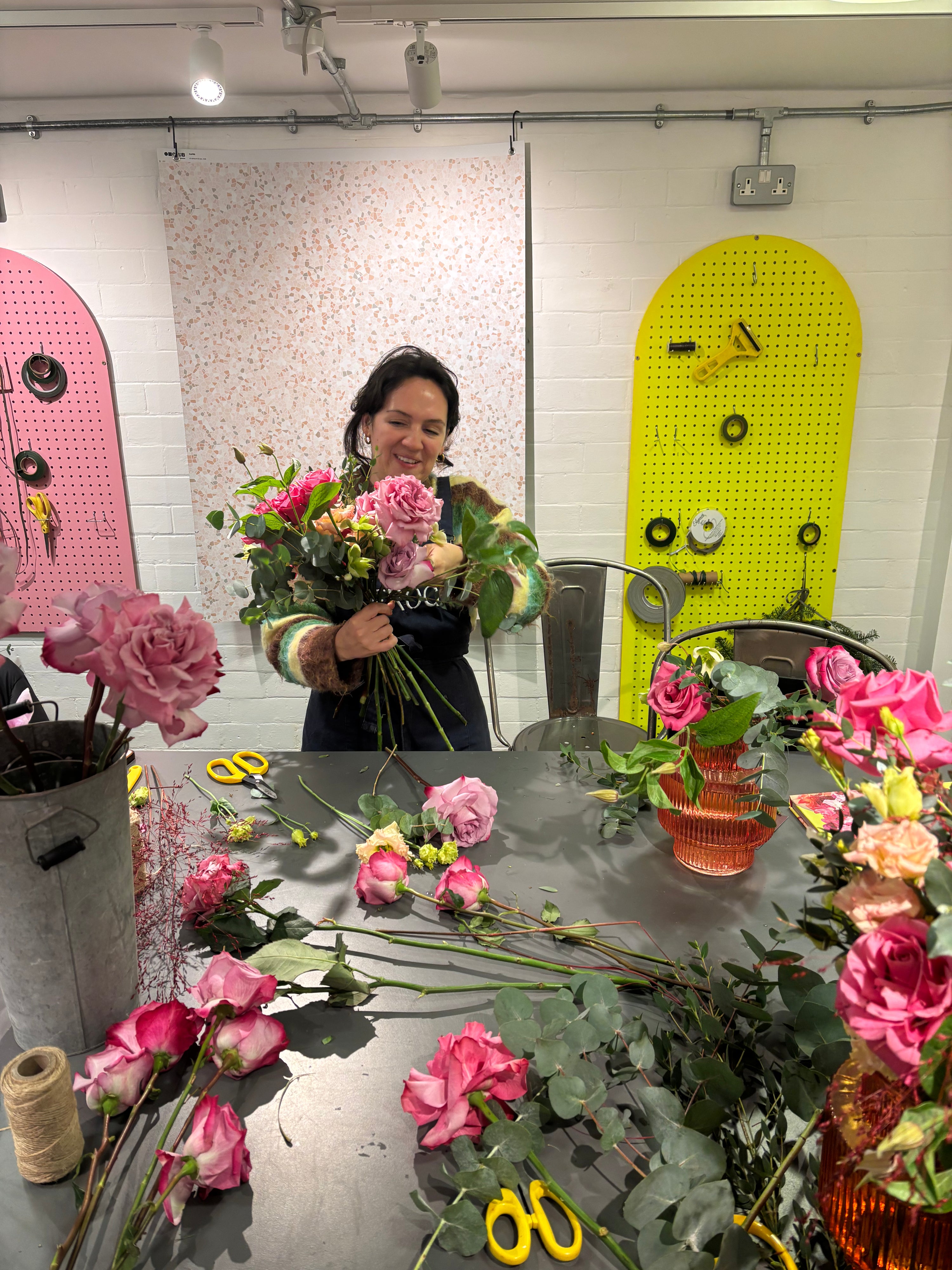 Person arranging flowers in a workshop with colorful doors in the background