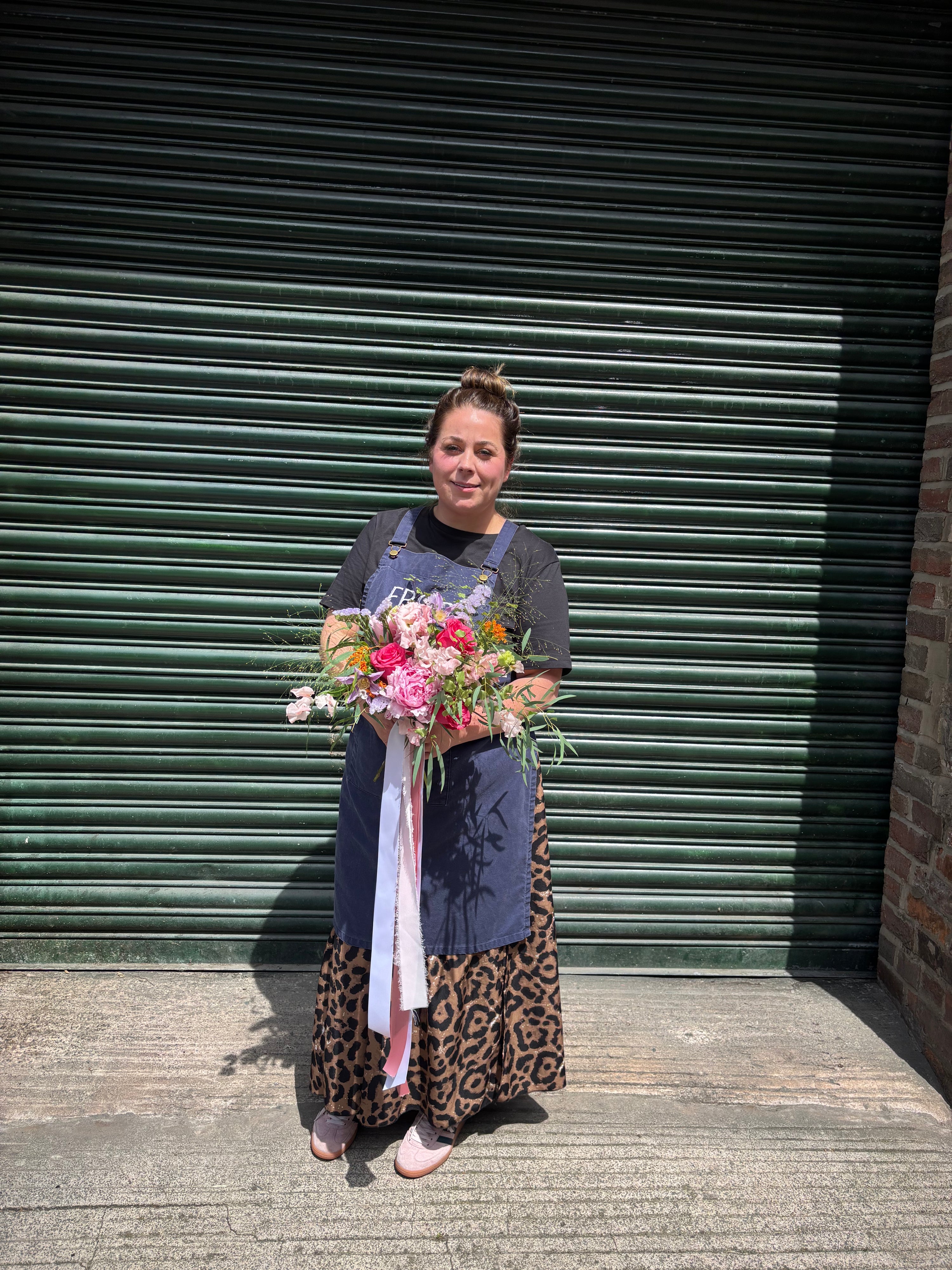 Woman holding a bouquet of flowers in front of a green shutter.
