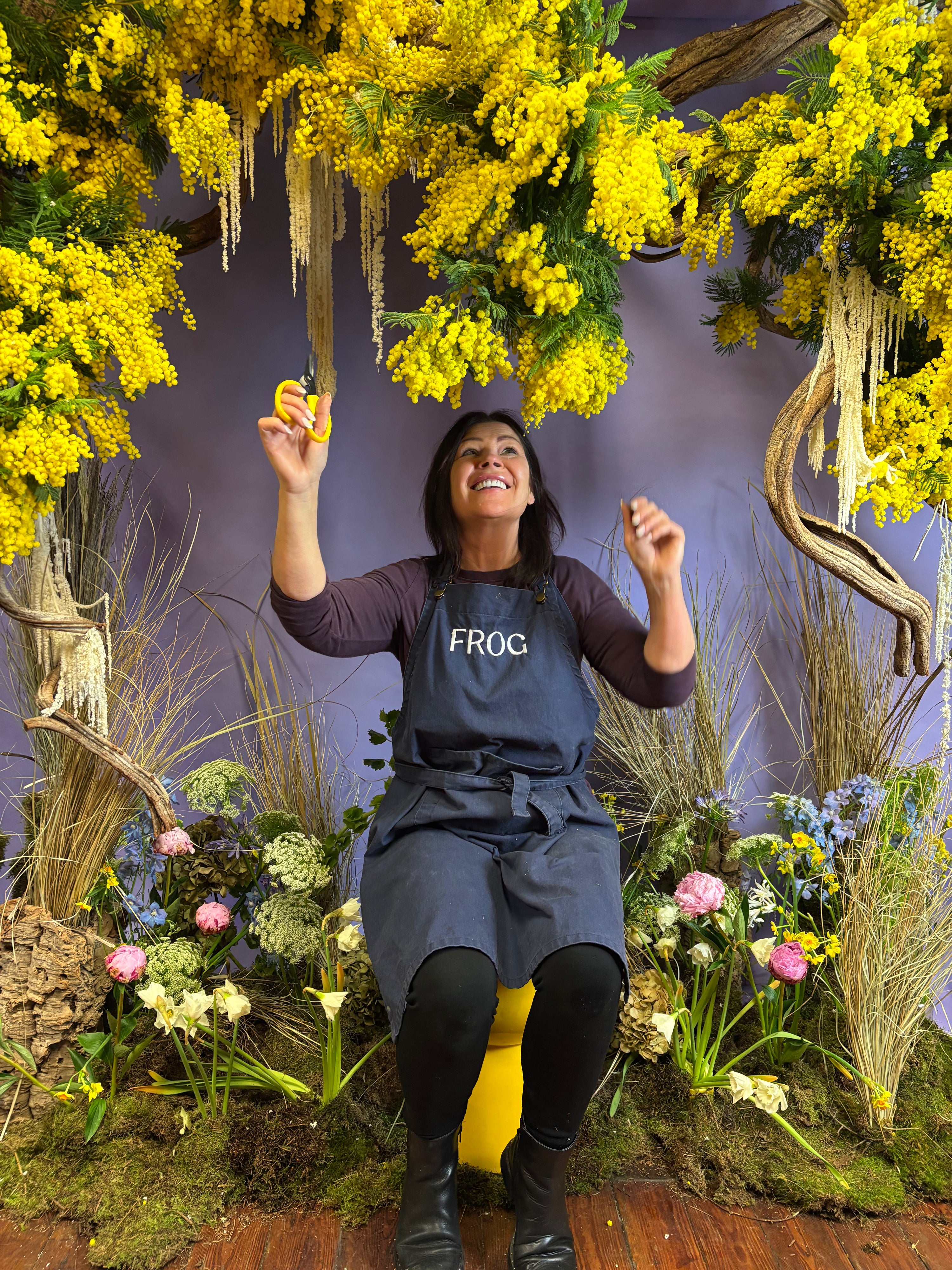 Person in a floral and nature-themed setting with yellow flowers and plants.
