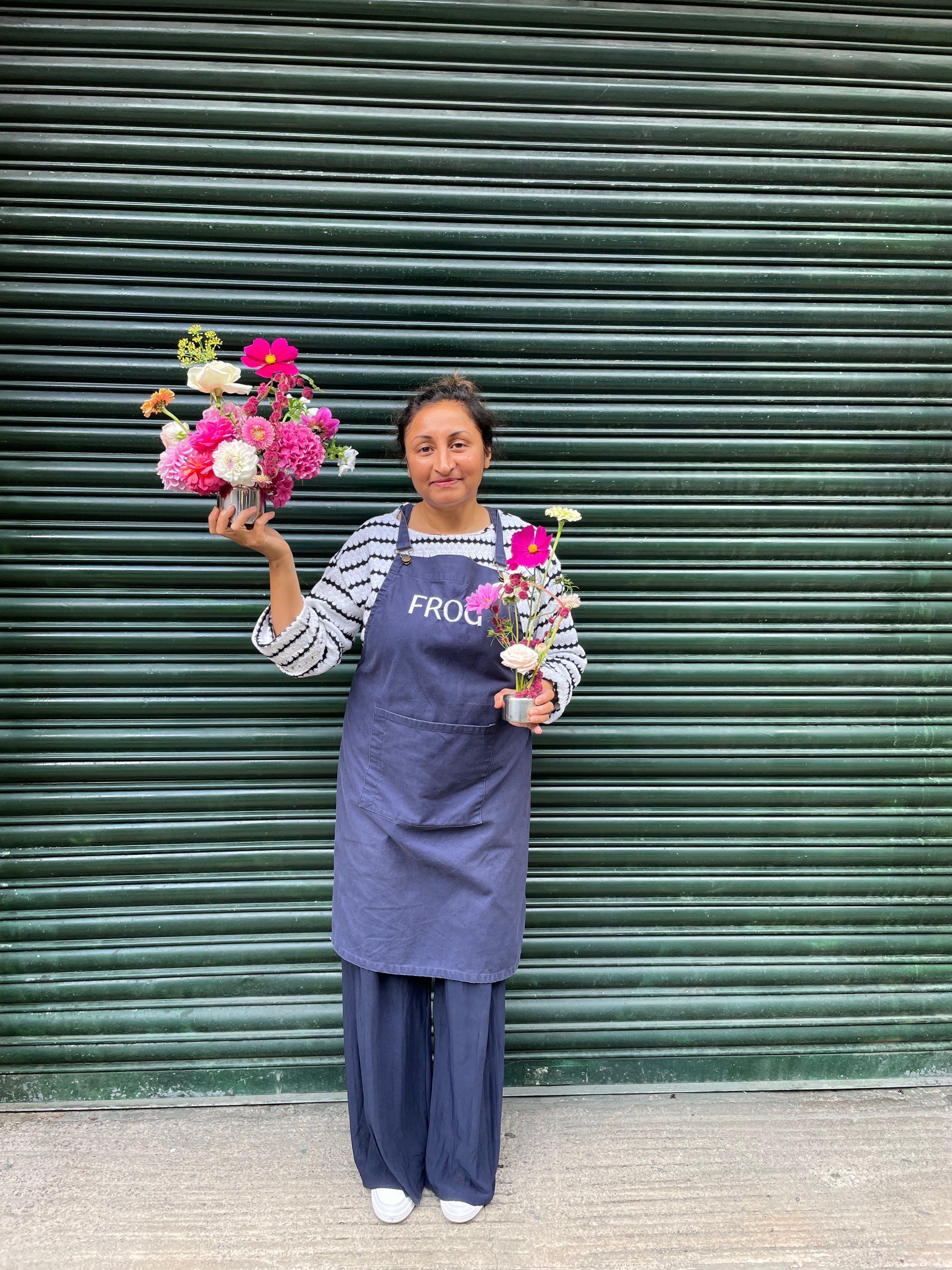Person holding flowers in front of a green shutter